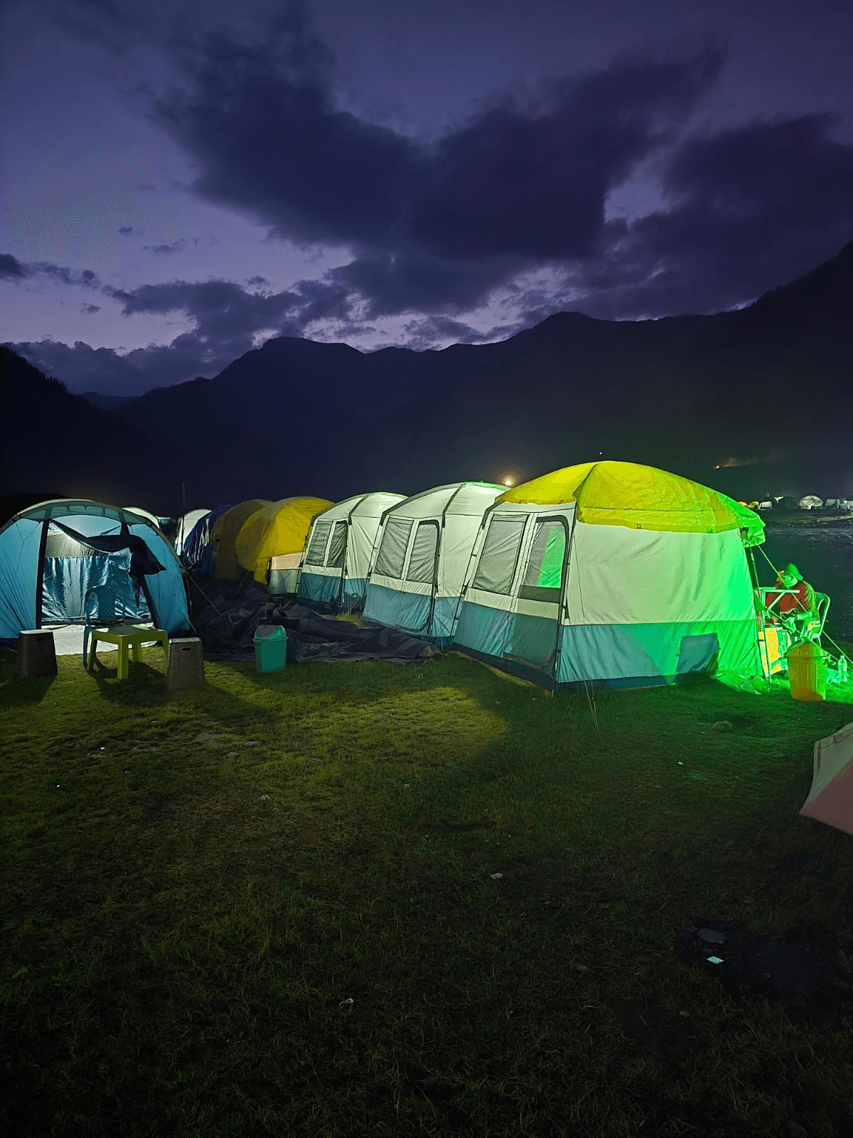 Camp tents glowing by the river at dusk in Gurez